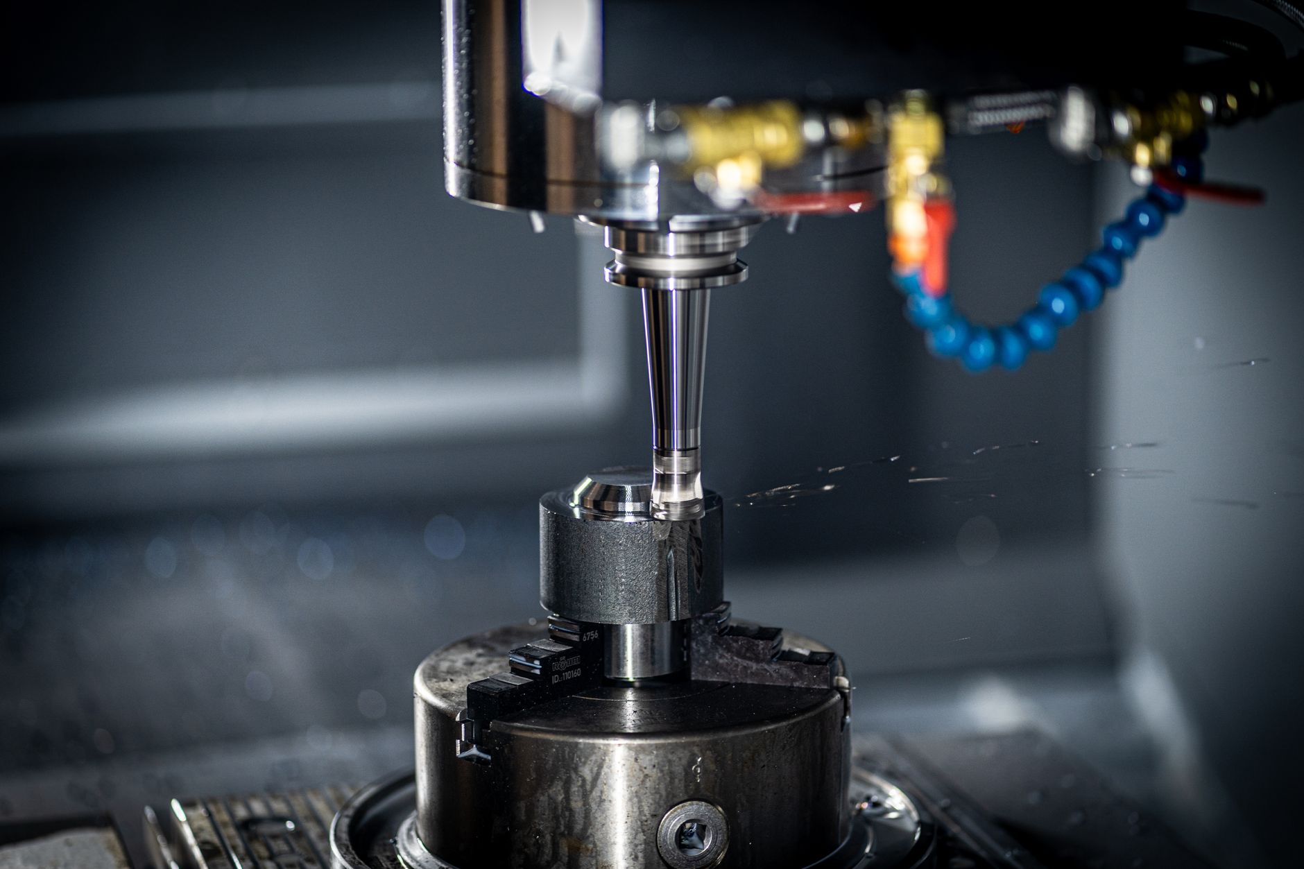 A CNC machine spindle with a tool holder and coolant lines mid-cut